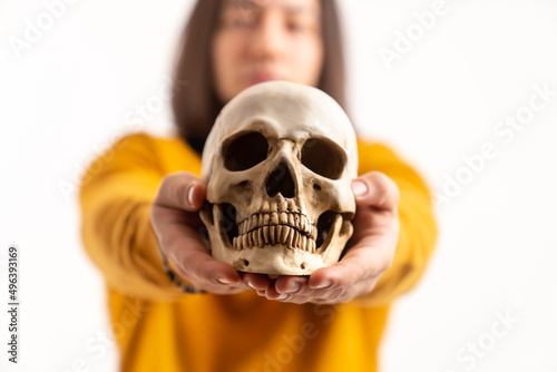 Portrait of a skeleton's skull model held by caucasian man wearing yellow sweatshirt. Isolated over white background. . High quality photo © PoppyPix