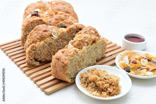 Healthy wholemeal big bread, with cereals, raisins, peanuts and honey on white wooden background