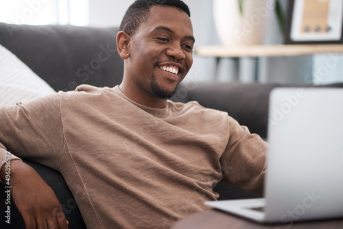 Social distancing does not have to equal isolation. Shot of a young man using a laptop at home. photo