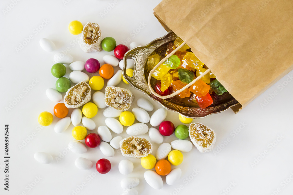 Colorful almond candies and chocolates designed on a white surface with a paper bag.Conceptual image of celebrations Colorful almond candies and chocolates designed on a white surface with a paper bag.Conceptual image of celebrations