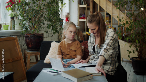 Mom helps the girl with lessons in a cozy living room