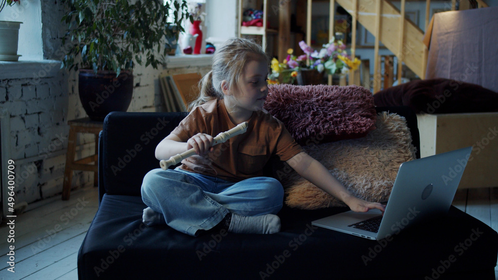A child opens a laptop and searches the Internet for a video lesson of playing the flute A child opens a laptop and searches the Internet for a video lesson of playing the flute
