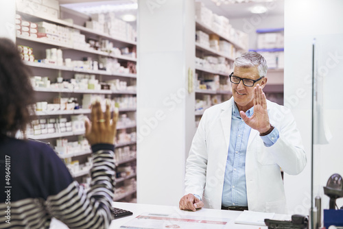 Have a great day. Shot of a cheerful mature male pharmacist greeting a customer inside of the pharmacy.