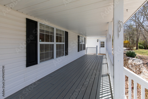 grey covered deck with white house showing some side yard