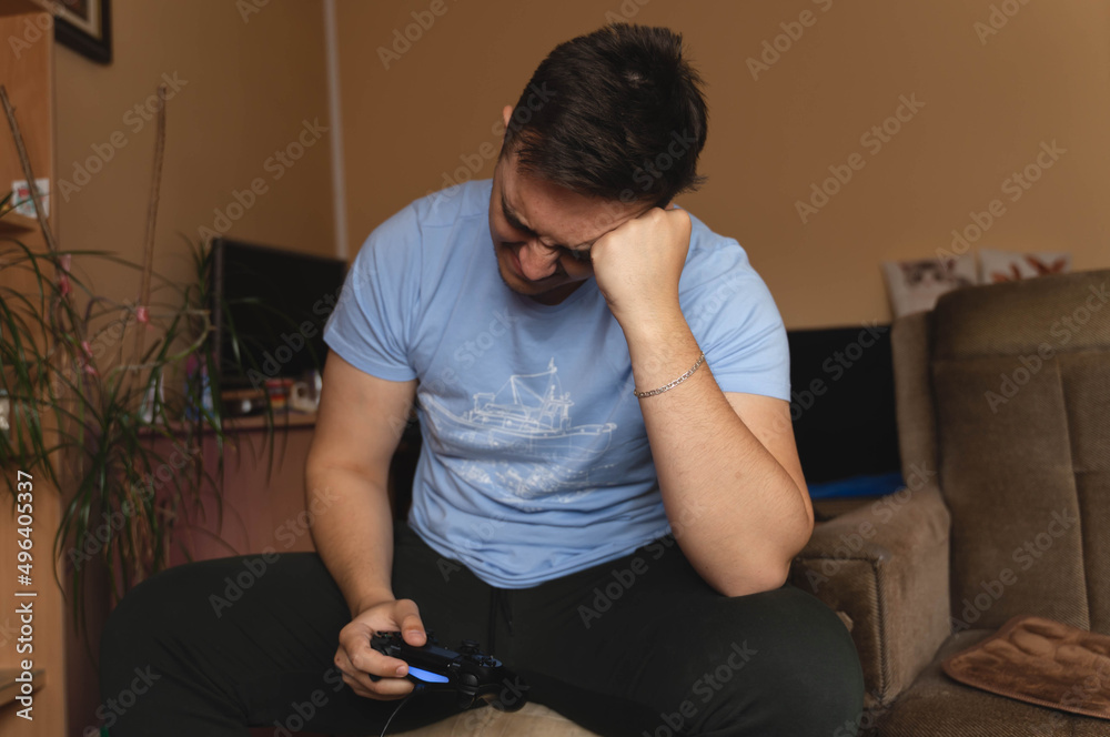 A one man playing video games in his room during the day