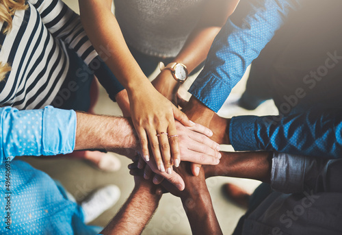 Getting it done through teamwork. Shot of a group of creative businesspeople standing with their hands in a huddle.