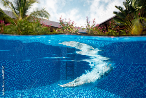 A view of a person dives into the pristine blue swimming pool at daytime.