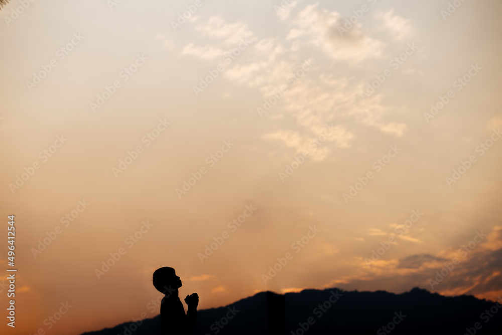 Silhouette of a man prayer on mountain at sunset. concept of religion.