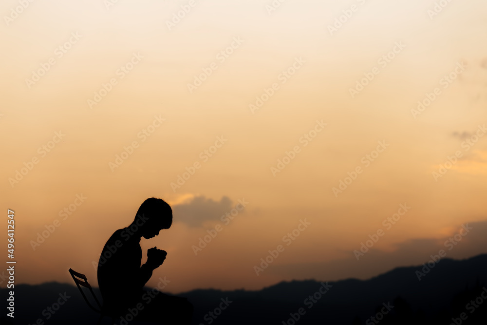 Silhouette of a man holding hands and prayer on mountain at sunset. concept of religion.