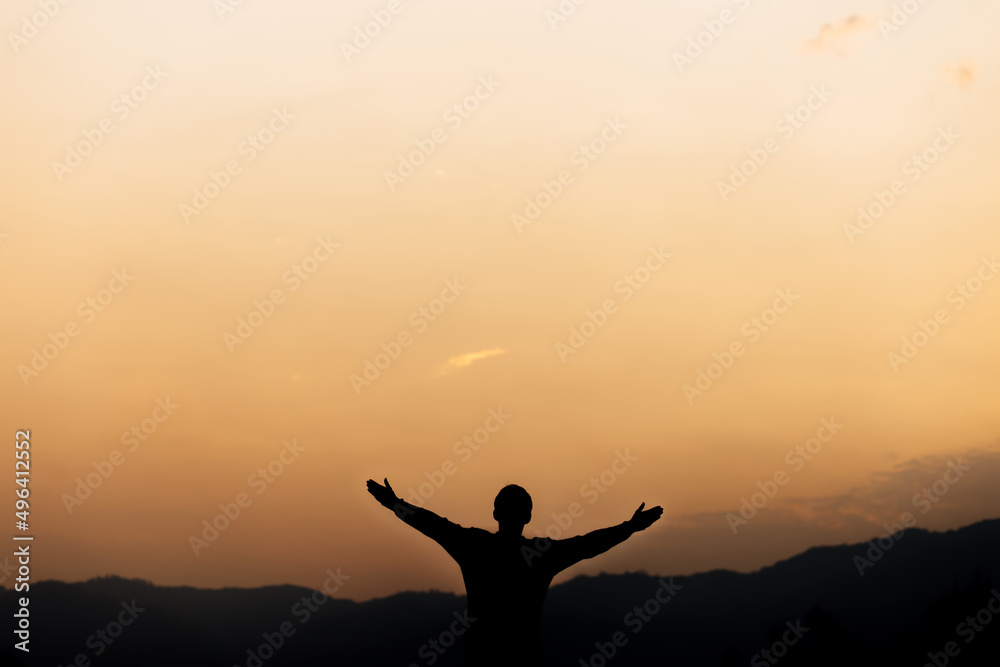 Silhouette of a man standing lift hands up and prayer and worship God at sunset. concept of religion.