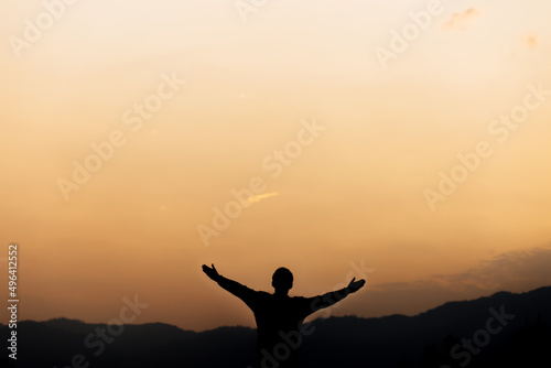Silhouette of a man standing lift hands up and prayer and worship God at sunset. concept of religion.