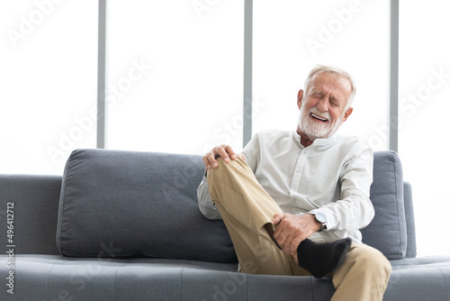 senior man suffering from knee ache on sofa © offsuperphoto