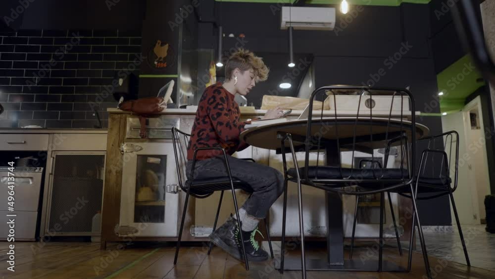 Ground view push-out of young woman using computer in empty restaurant Ground view push-out of young woman using computer in empty restaurant