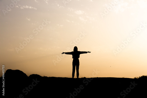 Silhouette of seductive woman on rooftop at urban sunset, Back view silhouette of unrecognizable female in opening hands alone in sunny autumn evening in countryside