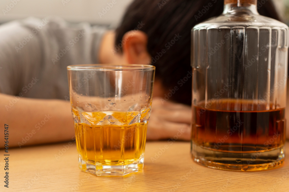 Alcohol addicted man sleeping at the table. Sad depressed male adult having troubles with alcohol. Alcohol addicted man sleeping at the table. Sad depressed male adult having troubles with alcohol.