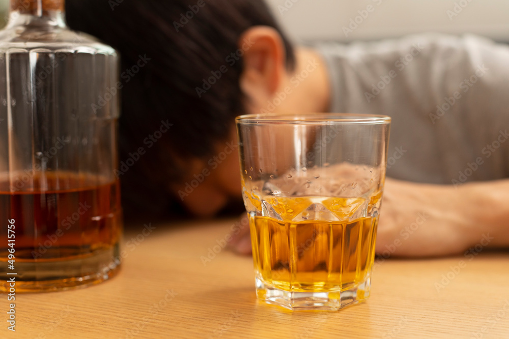 Alcohol addicted man sleeping at the table. Sad depressed male adult having troubles with alcohol. Alcohol addicted man sleeping at the table. Sad depressed male adult having troubles with alcohol.