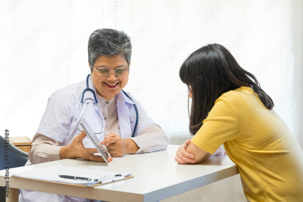 Asian girl and senior psychologist woman having therapy with digital tablet at clinic. Asian girl and senior psychologist woman having therapy with digital tablet at clinic.