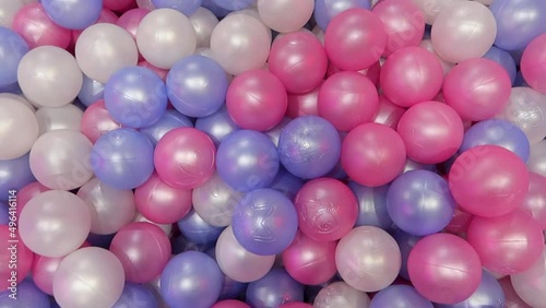 Colored pink blue and white plastic balls in pool for kids games in entertainment room