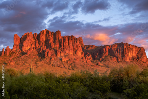 Stunning red sunset of the Superstition Mountains with purple and orange clouds.