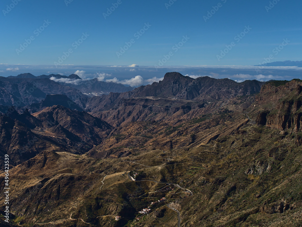 Beautiful aerial view of the western mountains of island Gran Canaria, Canary Islands, Spain on sunny day in winter seaon with winding country road.