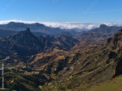 Stunning view of the colorful mountains of island Gran Canaria, Canary Islands, Spain with famous rock formation Roque Bentayga and sea of clouds.