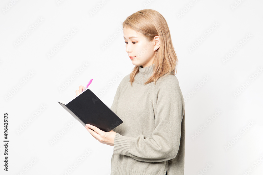 白い背景の前に立って筆記用具を持っている若い女性 白い背景の前に立って筆記用具を持っている若い女性