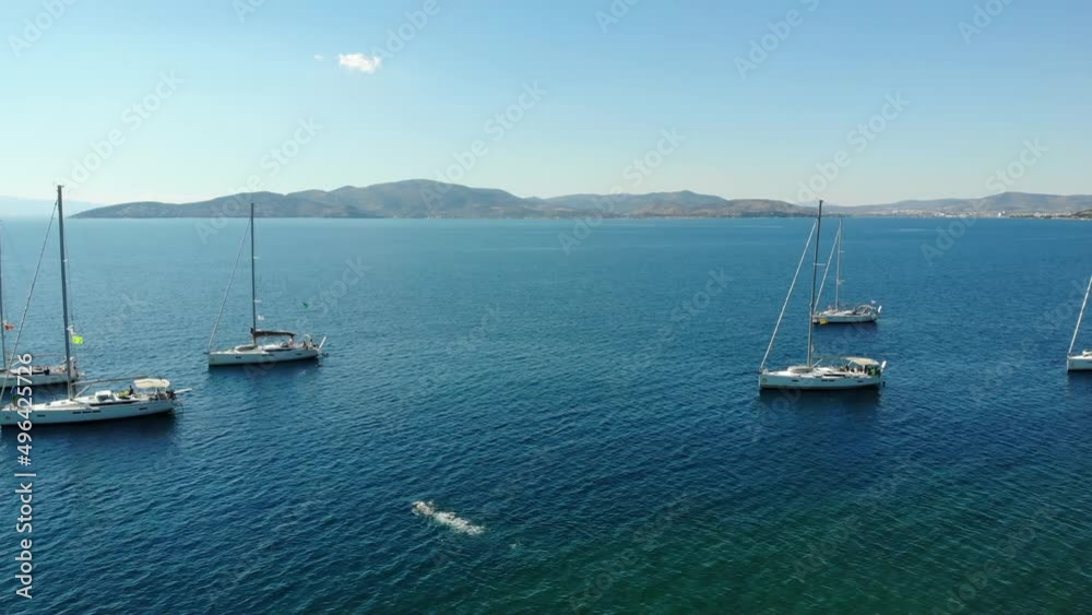 Segelboote als Flotille beim Ankern in Griechenland in blauem Meer und Wasser im Urlaub bei Sonne per Drohne als Schwenk gefilmt Segelboote als Flotille beim Ankern in Griechenland in blauem Meer und Wasser im Urlaub bei Sonne per Drohne als Schwenk gefilmt