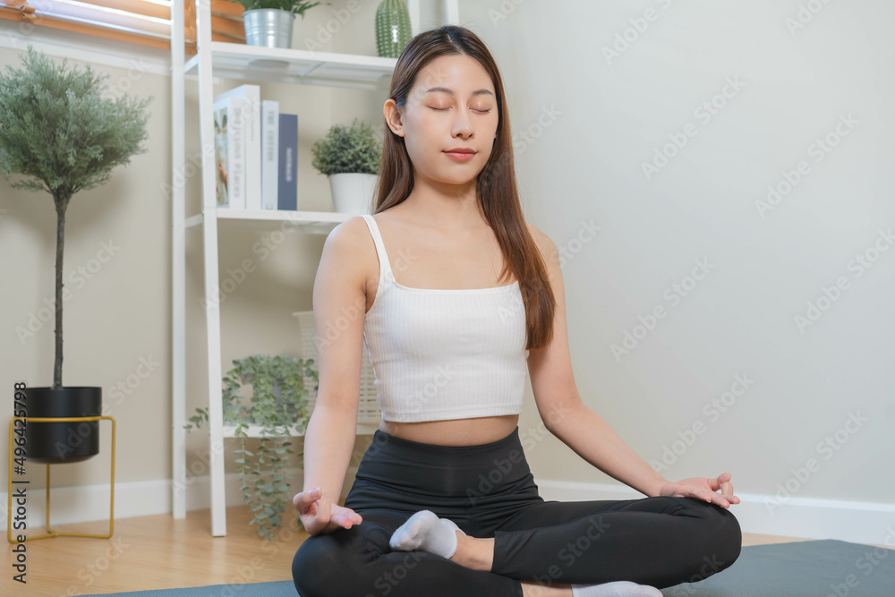 Workout, calm asian young woman, girl hand in calm pose sitting practice meditating in lotus position on mat at home, meditation, exercise for wellbeing, healthy care. Relaxation, happy leisure. Workout, calm asian young woman, girl hand in calm pose sitting practice meditating in lotus position on mat at home, meditation, exercise for wellbeing, healthy care. Relaxation, happy leisure.