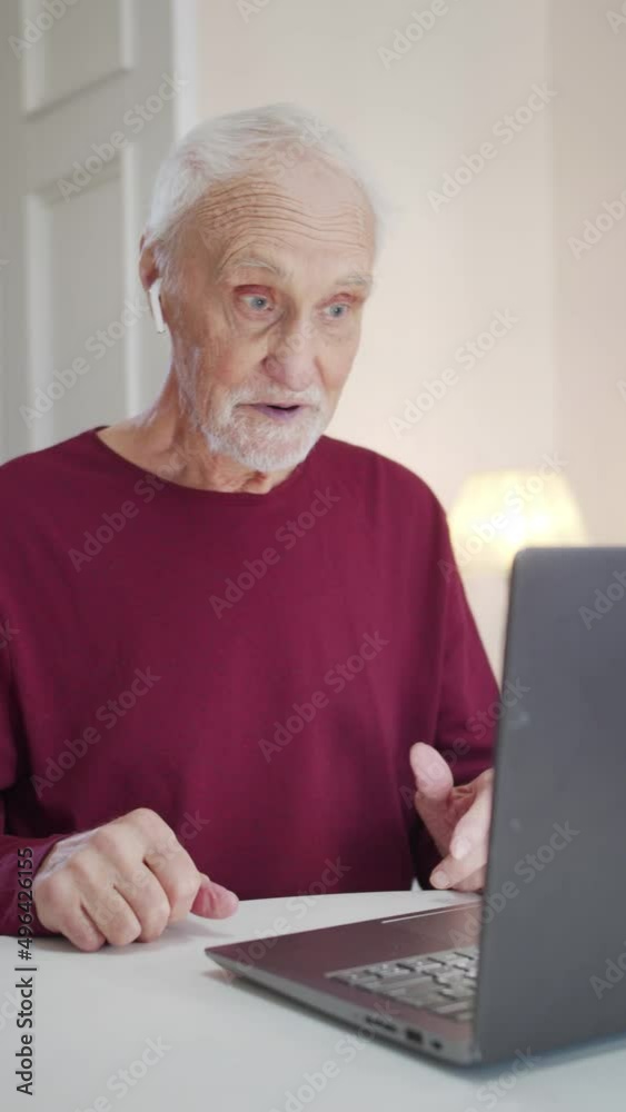 An elderly man is using a video call on a laptop to talk to his family. He explains and tells An elderly man is using a video call on a laptop to talk to his family. He explains and tells