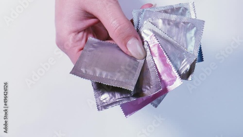 Women's hands choose a pink condom package among silver ones. Special sexual relationship.