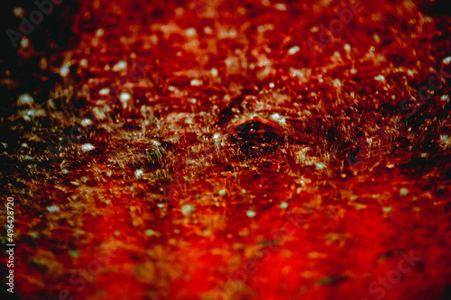 Abstract, red and dramatic bubbles and bristles on the windscreen of a car going through a carwash. 