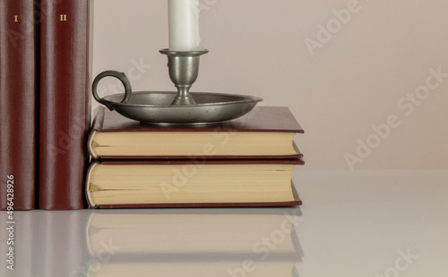 Candle holder and old style books against white background