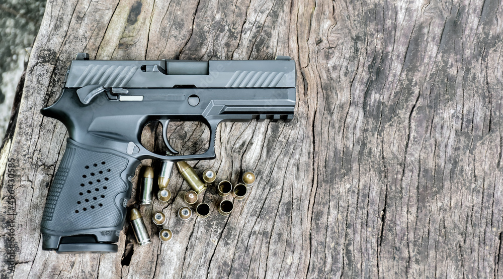 Obraz premium 9mm automatic pistol and bullets on wooden table, soft and selective focus on pistol, copy space.