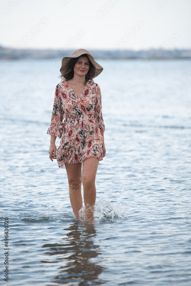 Attractive woman wearing hat walking in the sea. Summer vacation Cyprus