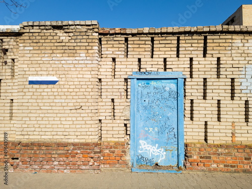 Textured yellow brick wall and blue door. Space for text.
