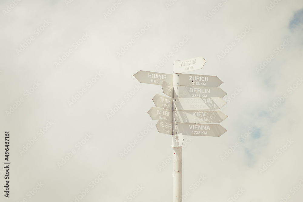 White pointer with multiple arrow-heads on cloudy sky background, city names White pointer with multiple arrow-heads on cloudy sky background, city names