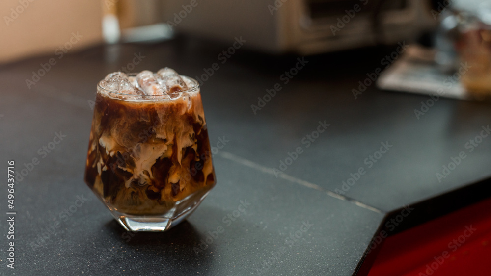 Ice coffee on table with cream being poured into it showing the texture and refreshing look of the drink