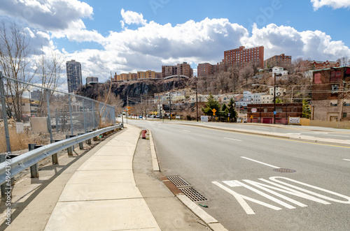 Road at Cliffside Park, New Jersey with residential buildings on top of a rock during a sunny winter day, horizontal
