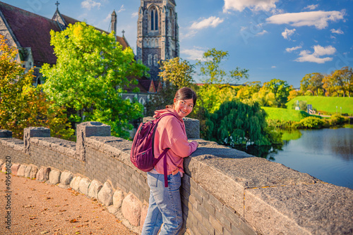Photography A beautiful young smiling brunette woman stands on a stone bridge near the St