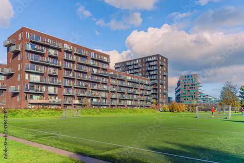 Photography Modern brown residential apartment building near the Byparken park and football field in Ørestad