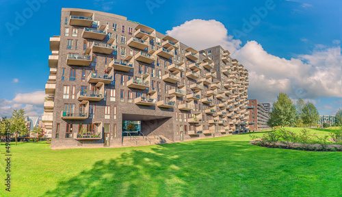 Fényképezés modern futuristic residential house with rectangular balconies near a green Byparken park in Ørestad city area