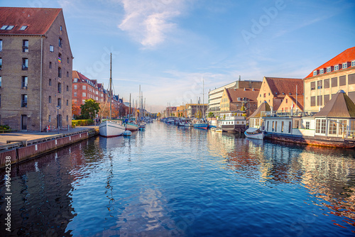 River canal with many boats and ships with small old houses in the neighbourhood area Christianshavn in Copenhagen, Denmark