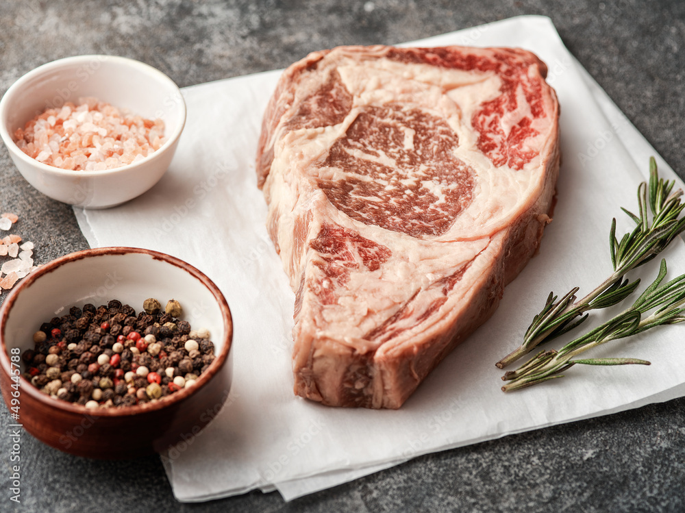 Raw entrecote on white paper. Preparing raw beef steak for barbecue grill.