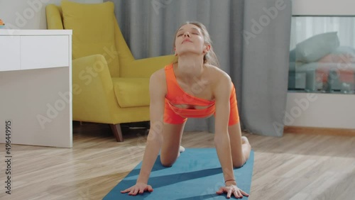 Young pretty woman in orange sports suit working out on yoga mat