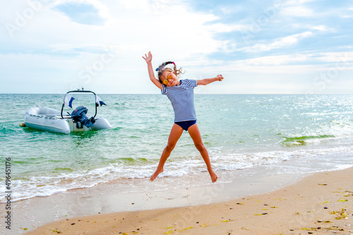 little girl jumping on the beach on the blue seashore in the summer holidays during the daytime 