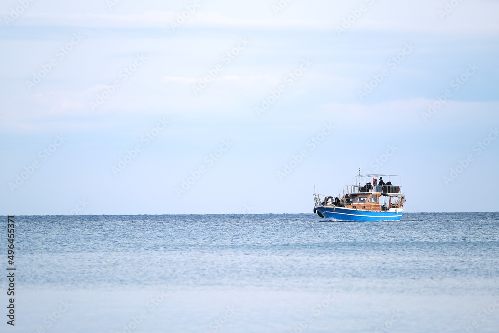 Blue boat with people in the sea in the distance on the horizon