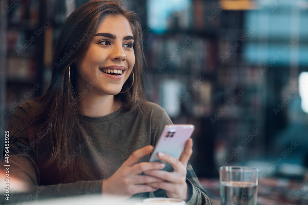 Woman using smartphone and drinking coffee in a cafe. Woman using smartphone and drinking coffee in a cafe.
