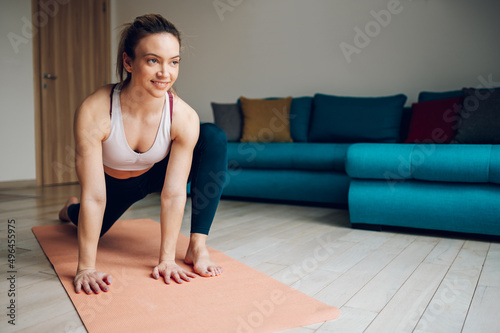 Athletic young woman practicing yoga on a fitness mat at home