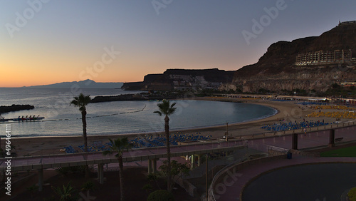 View of beach Playa de Amadores in holiday resort Puerto Rico on the southern coast of Gran Canaria, Canary Islands, Spain after sunset with Tenerife.