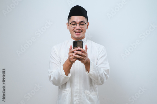 Happy asian muslim man holding and pointing on phone cellular